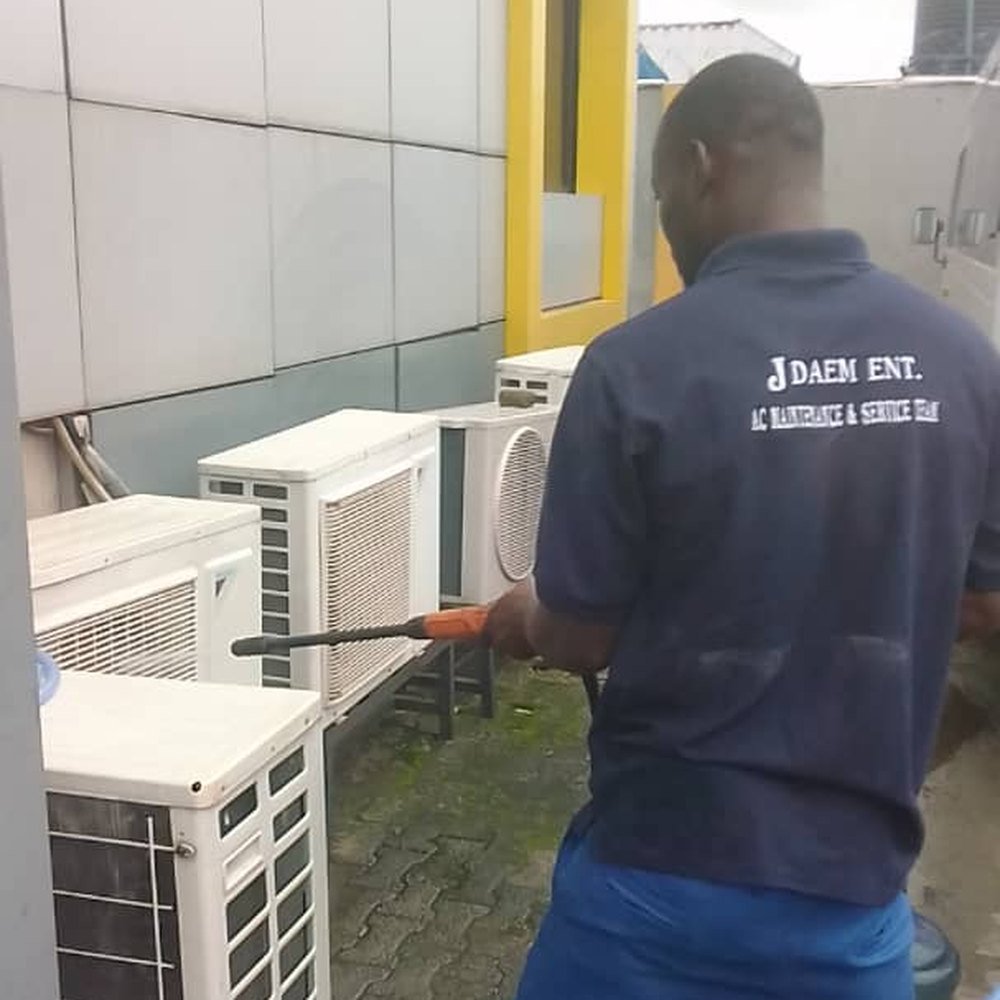 JDAEM technician pressure washing a bank of commercial AC condensers