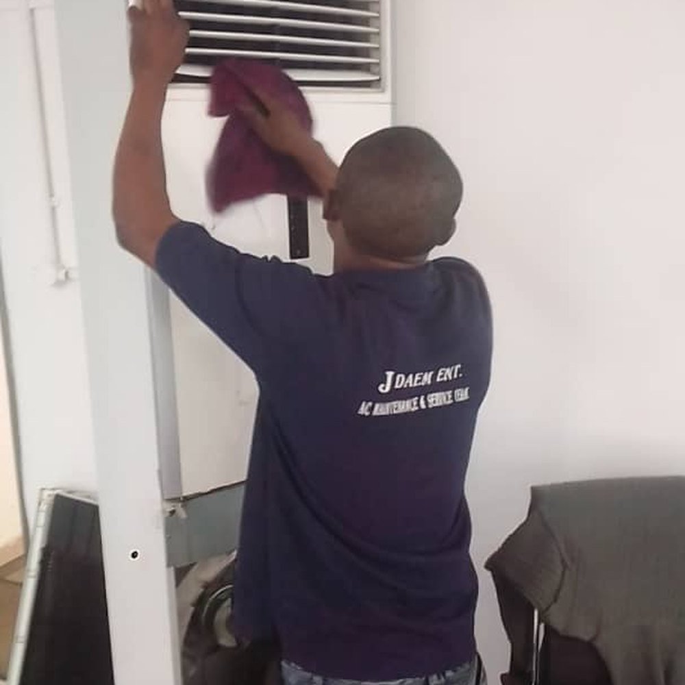 JDAEM technician cleaning a floor-standing package AC unit