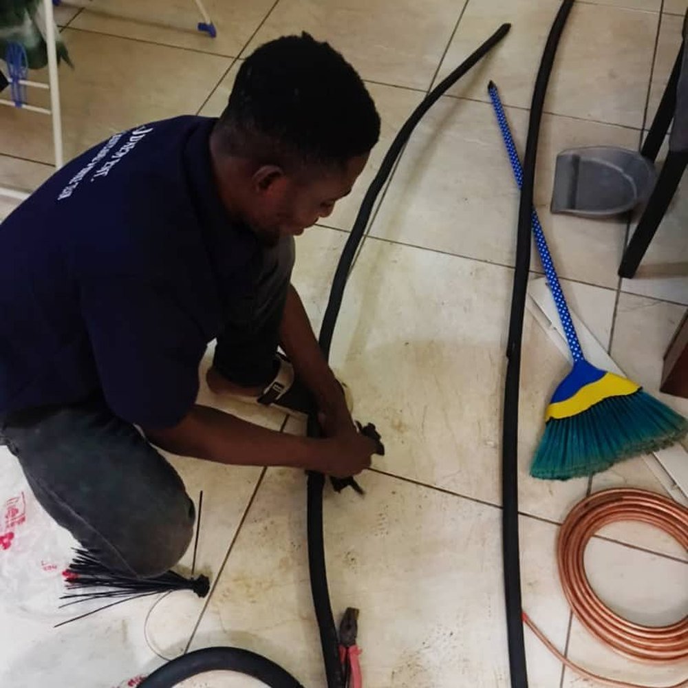 JDAEM technician preparing insulated copper refrigerant pipework for installation