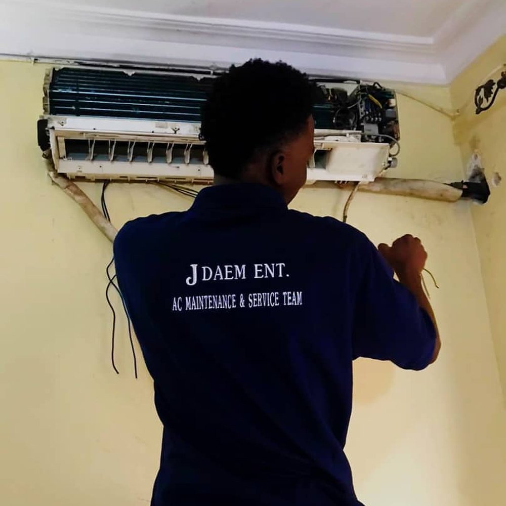 JDAEM technician servicing a wall-mounted split AC indoor unit